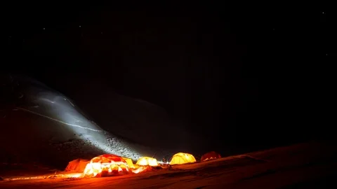 Timelapse of stars moving quickly across sky above lit up tents in winter camp Stock Footage 124238719