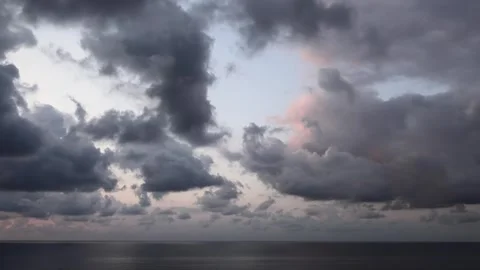 Timelapse storm clouds build above the sea with sunset glow and shifting light Video stock 339476453
