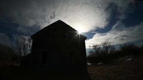 Timelapse of summer clouds moving behind a dilapidated farmhouse with a dramatic Stock Footage 335549993