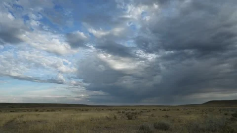 Timelapse of summer white to gray clouds drifting above dry grassing plains as Stock Footage 310690698