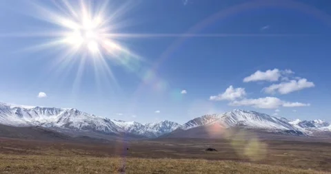 Timelapse of sun movement on crystal clear sky with clouds over snow mountain Stock Footage 131579996