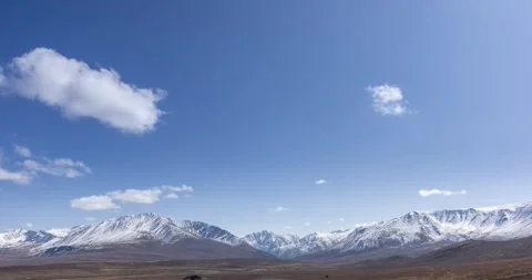 Timelapse of sun movement on crystal clear sky with clouds over snow mountain Stock Footage 288831960