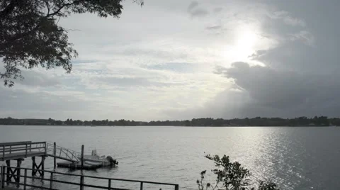 Timelapse of Sun Peeking Out from Behind Clouds Above River on Steely Grey Day Stock Footage 58188837
