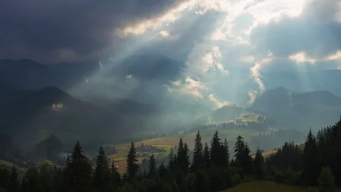 Timelapse of sun rays emerging though the dark storm clouds in the mountains wit Stock-Footage 76461180