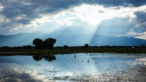 Timelapse of sun rays through clouds with reflection on water in sunset Stock Footage 76019115