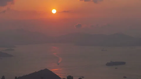 Timelapse sun sets behind Hong Kong harbor with motorboats Video stock 121896833