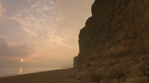 Timelapse - sun sets next to large towering cliffs by the sea Stock Footage 47811898