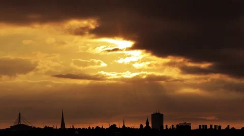 Timelapse of sun setting down behind golden evening sky over city skyline Stock Footage 49990425