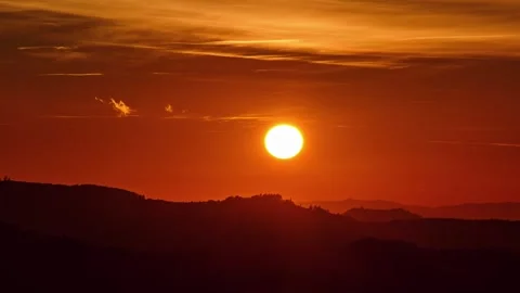 Timelapse of the sun setting over mountain ridge with warm orange sky and fading Stock-Footage 319830977
