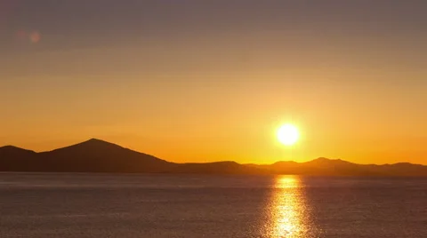 Timelapse sunrise, sun rising behind hills over sea. Stock Footage