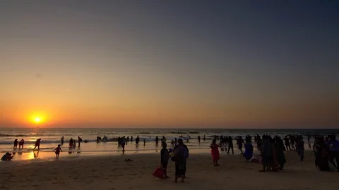 Timelapse of Sunset on a beach with crowd walking in the foreground Stock Footage 78020629