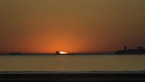 Timelapse of sunset with big sun silhouette of ferry and freighter crossing sun Stock Footage 155157383