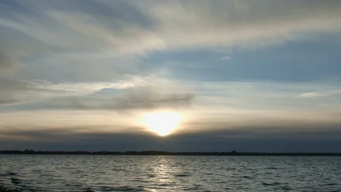 Timelapse of sunset with clouds and blue sky over cold lake or river 動画素材 96019184