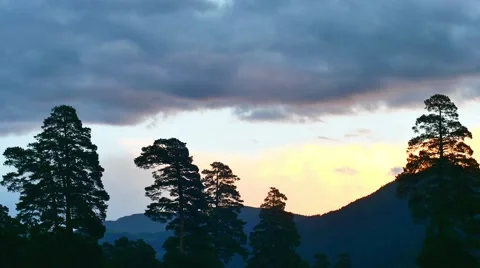Timelapse of sunset with clouds in mountain forest, motionless silhouettes of Stock Footage 65567011