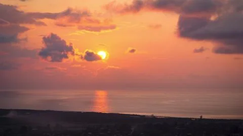 Timelapse of Sunset in the Clouds over the Sea and the City, aerial view. Stock Photos