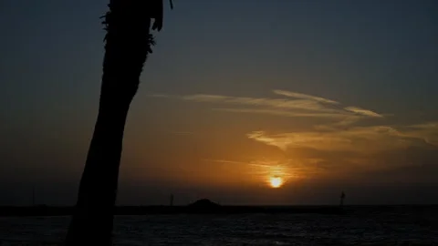 Timelapse of sunset over the Aegean Sea. Palm trees and a small stone bay are Stock Footage 254716164