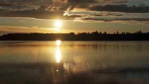 Timelapse of sunset over calm lake and low flying clouds. Sun reflection Stock Footage 116480200