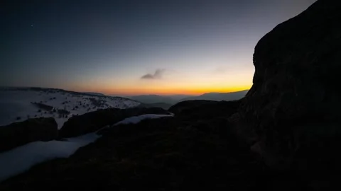 Timelapse of sunset over snowy mountains with rocky foreground and vibrant sky Stock Footage 340251990