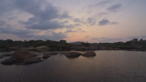 Timelapse of sunset on the river bank with rocks in the foreground 스톡 동영상 87318976