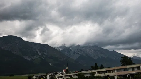 Timelapse of thunderstorm clouds moving over mountains and village in austria Stock Footage 249805243