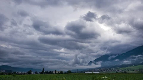 Timelapse of thunderstorm clouds moving over mountains and village in austria Stock Footage 249806829