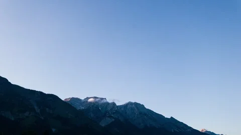 Timelapse of tiny cloud moving over silhouette of mountain in austria Stock Footage 249804124