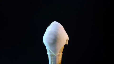 Timelapse of vanilla ice cream in waffle cone melting on black background Stock Footage 247128904