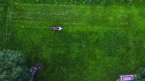 Timelapse video of a man mowing the grass. The lawnmower man. Aierial view. Stock Footage 139252797