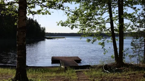 Timelapse video over a calm lake with a wooden pier framed by trees. Horizontal. Stock Footage 341361366