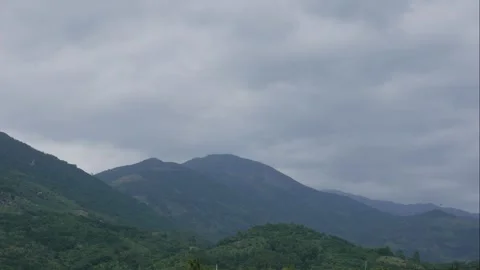 Timelapse view of distant mountains under a cloudy sky, with low vegetation near Stock Footage 331144927