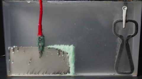 Timelapse view of electrolysis. Nickel plate deteriorates and collects mineral Stock Footage 320466358
