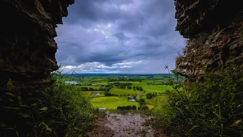 Timelapse view from rocky cave of storm clouds over green valley Stock Footage 345467196