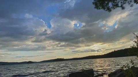 Timelapse view of sun setting over a Canadian lake behind dancing clouds Stock Footage 201488428