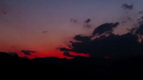 Timelapse of Vivid Sunset Clouds Drifting Over Dark Mountain Silhouettes 動画素材 336758486