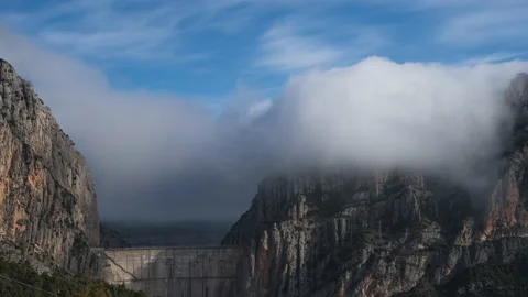 Timelapse of a waterfall of clouds falling between the mountains above a dam Stock Footage 146155894