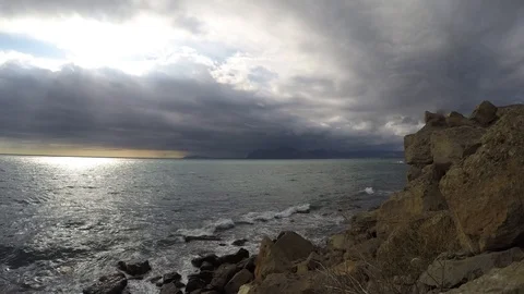 A timelapse waves beat about coastal stones and clouds fly to the sun Stock Footage 99719767