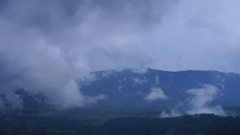 Timelapse of white clouds and fog moving fast over mountain forest under blue sk Stock Footage 340186172