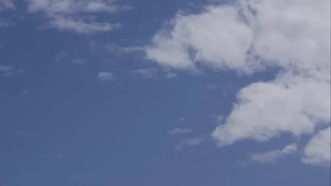 Timelapse of white clouds drifting across a clear blue sky above an open daytime Видео 341111865
