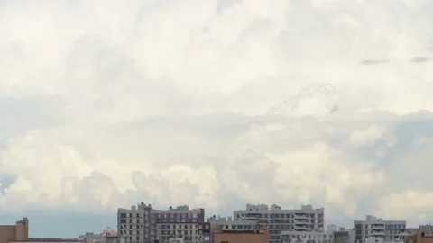 Timelapse, white cumulus clouds are rapidly floating over the roofs of city buil Video stock 228489833