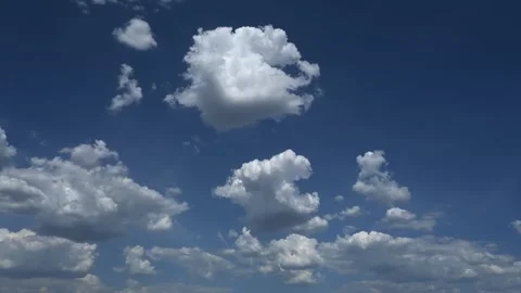 Timelapse of white cumulus clouds growing and moving through a bright blue Stock Footage 335898182