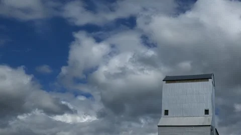 Timelapse of white cumulus clouds moving behind a silver-gray colored grain Stock Footage 336807539