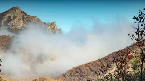 Timelapse white mist flies over a mountain range at the foot of which is an autu Stock Footage 171724898