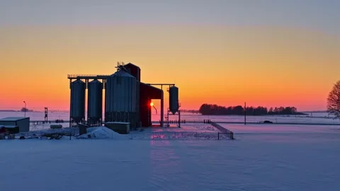 Timelapse of a winter sunrise behind grain silos and a farm elevator, glowing Vídeos de archivo 327304532