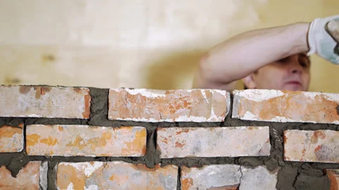 Timelapse A worker erects a brick wall indoors. Stock Footage 242189780
