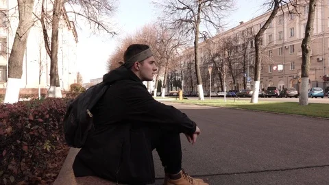 Timelapse of a young man sitting still on the sidewalk in a crowd of people Vídeo Stock 118957532
