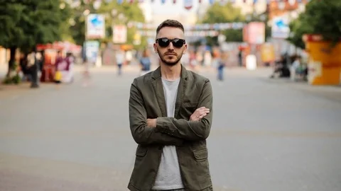 Timelapse of Young man in sunglasses standing still at sidewalk in crowd traffic Stock Footage 76864604