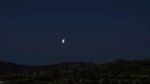 Timelpase of Eclipsed Moon Setting Behind Mountains Night To Day Stock Footage 89137870