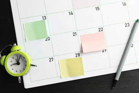 Timetable. Planner with sticky notes, pen and alarm clock on black wooden t.. Stock Photos