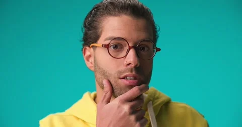 Timid nerd guy with glasses touching chin, looking away and thinking, having Video stock 230127868