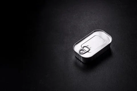 Tin or aluminum rectangular can of canned food with a key on a dark concrete  Foto stock